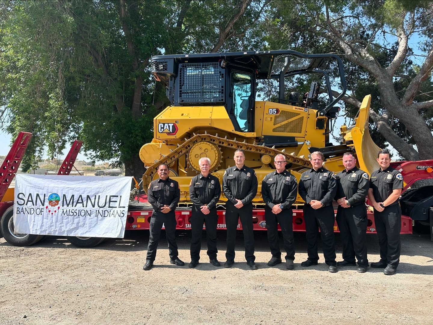 County and San Manuel Fire leadership stand in front of new bulldozer used for fire fuel mitigation